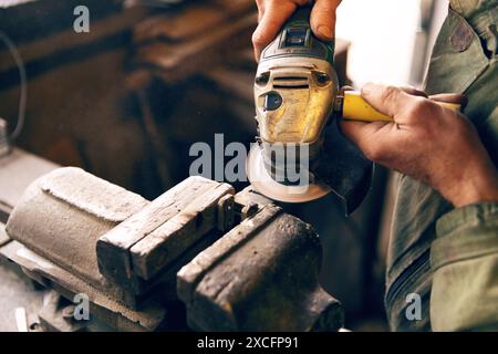 Close-up of hands using an angle grinder on metal at a workbench Stock Photo