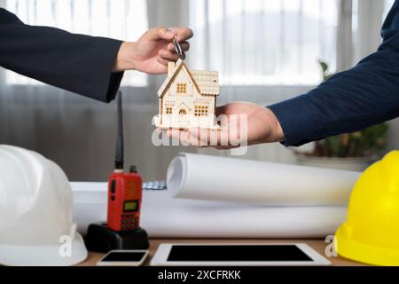 Hand in hand between project contractors and customers due to negotiation of expenses and investments, construction and repair of residential building Stock Photo