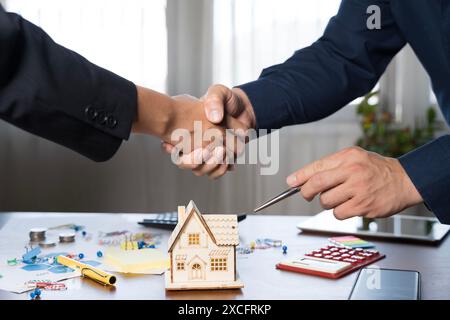 Real estate agent and customer shaking hands celebrating after successful agreement and signing house contract. Home insurance concept and investment Stock Photo