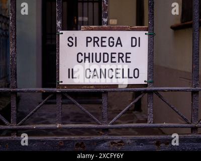 Cremona, Italy - June 10th 2024 Close the gate sign written in italian hanging on a rusty metal fence Stock Photo