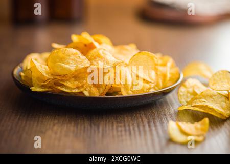 Crispy Potato Chips on plate on a wooden table. Stock Photo