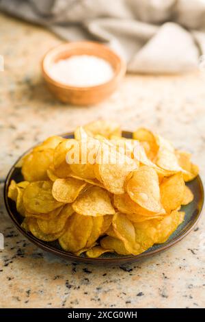 Crispy Potato Chips on plate on a kitchen table. Stock Photo