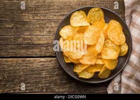 Crispy Potato Chips on plate on a wooden table. Top view. Stock Photo