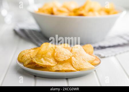 Crispy Potato Chips on plate on a white table. Stock Photo