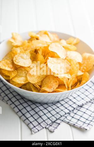 Crispy Potato Chips in bowl on a white table. Stock Photo