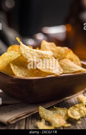 Crispy Potato Chips in bowl on a wooden table. Stock Photo