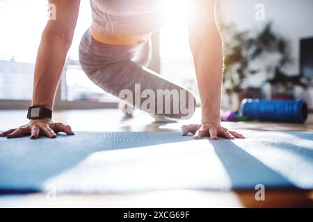 Beautiful redhead woman's home fitness routine. Home workout on gym mt in living room, sporty woman wearing sportswear clothes. Stock Photo