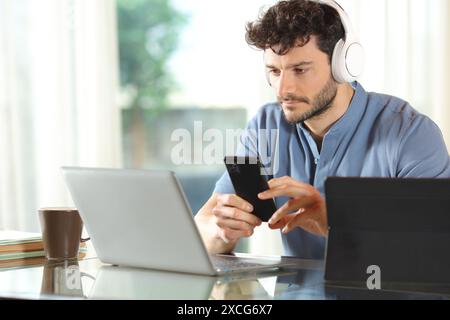 Serious man using multiple devices sitting at home Stock Photo
