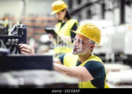 Warehouse employees in warehouse. Two workers in reflective clothing in modern industrial factory, heavy industry, manufactrury. Stock Photo