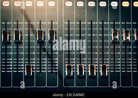 Audio mixer faders with mute buttons, professional sound equipment used in music production and live performances. Mixing console in recording studio close up top view. Stock Photo