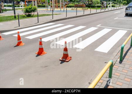 Applying road markings. Pedestrian crossing on the street in the yard. Cones on highway Stock Photo