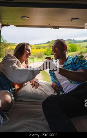 Happy diverse couple lying in van and spending time together Stock Photo