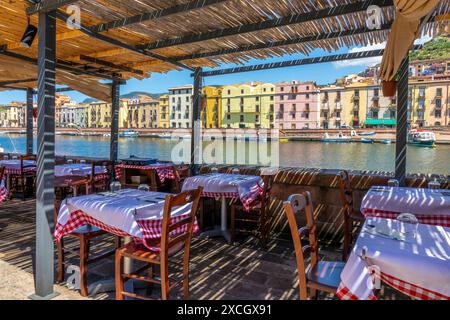 Outdoor terrace of an Italian restaurant with a view on the river and the colorful houses of the village of Bosa, Sardinia island, Italy Stock Photo