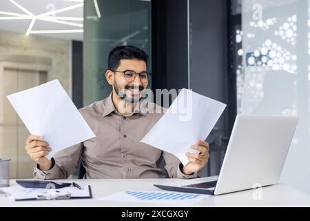 Successful mature experienced financier on paper work, Arab smiling satisfied with results of financial achievement, reviewing contracts, invoices and statements with accounts, businessman . Stock Photo