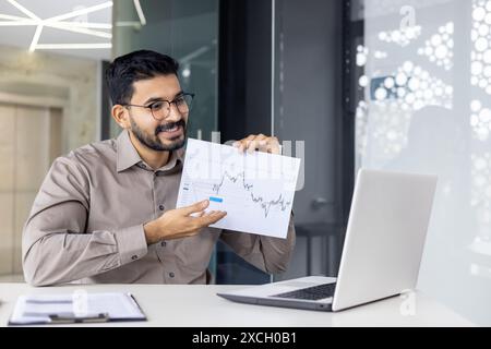 Confident businessman displaying financial chart during an online presentation. Professional discussing market trends in a modern office setting. Stock Photo