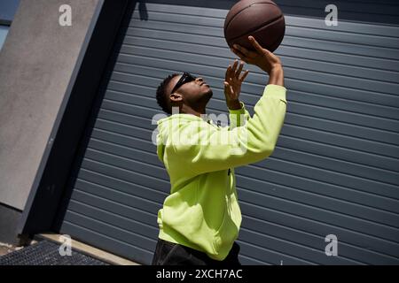 Handsome man in green hoodie catches basketball. Stock Photo