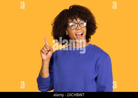 Smiling Young Man With Glasses Points Upward Stock Photo