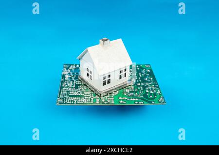 Smart, automated house concept, miniature house connected to a chipset,  on blue Stock Photo