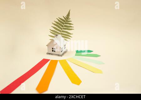 Energy efficiency rating chart, model miniature house and green fern leaf on beige Stock Photo