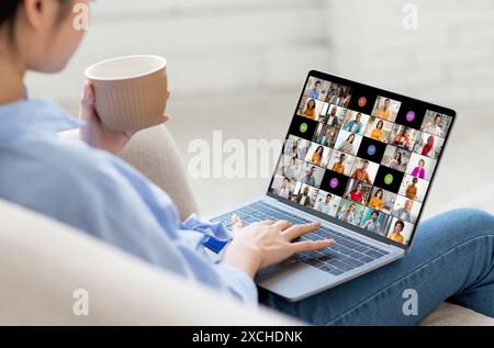 Woman Sitting on Couch Using Laptop for Online Video Conference Stock Photo