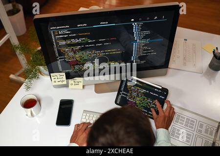 IT specialist reviewing programming code on laptop and tablet computer Stock Photo
