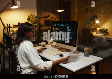 Developer reading document when working on programming code Stock Photo