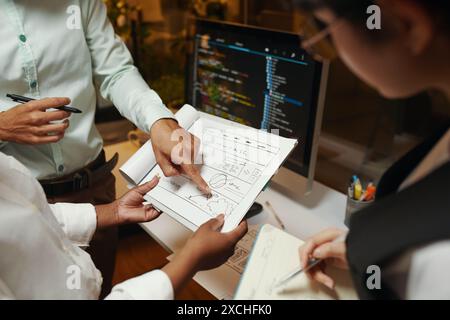 Closeup image of UI and UX designers discussing sketch of website design Stock Photo