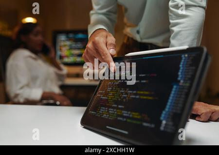 Closeup image of developer pointing at programming code on tablet screen Stock Photo