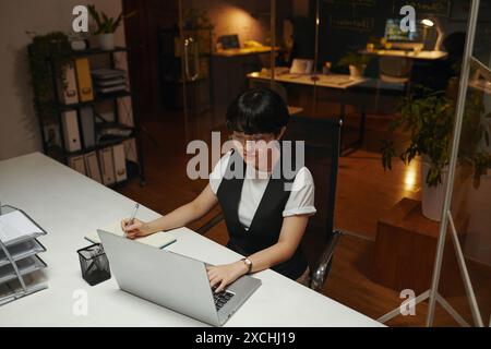 Young Asian programmer working on laptop in office late at night Stock Photo