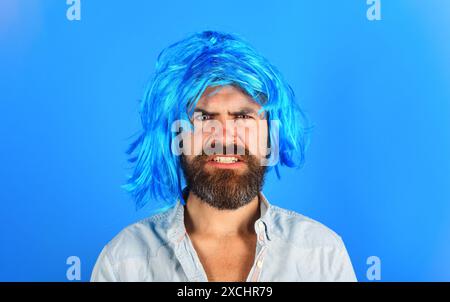 Angry man with beard and mustache in blue wig. Fashion concept. Handsome male in colored periwig. Barbershop advertising. Stylish guy with blue hair. Stock Photo