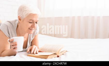 Woman Reading Book and Drinking Coffee on Bed Stock Photo