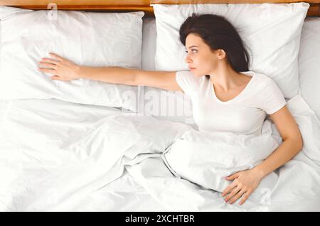 Woman Reaching for Empty Pillow in Bright Bedroom Morning Stock Photo