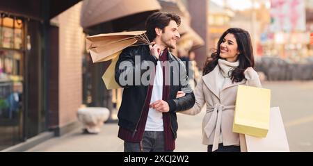 Happy shopaholics walking with shopping bags after making purchases Stock Photo