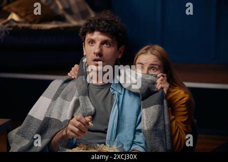 Young couple watching scary movie together Stock Photo