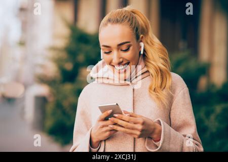 Young Woman Smiling While Using Smartphone Outdoors Stock Photo