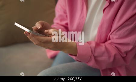 Unrecognizable woman at couch sofa hands fingers typing chat message girl female lady influencer user using mobile phone browsing smartphone app Stock Photo