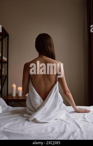 Woman client wrapped in towel sitting on massage table Stock Photo
