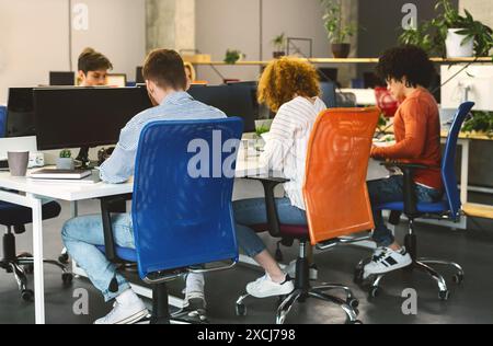 Back View of People Sitting at Table Working on Computers Stock Photo