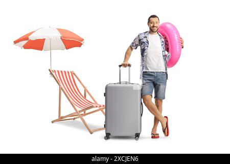 Man with a suitcase smiling and holding a swimming ring next to a beach chair isolated on white background Stock Photo