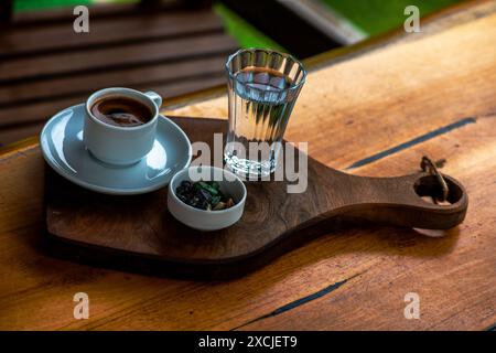 Turkish coffee presentation with pebble chocolate and a glass of water, showcasing a traditional, elegant setup on the table. Stock Photo