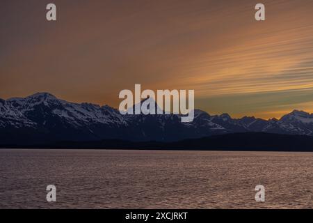 Inner Passage Alaska Cruise snow capped Mountain landscape with orange sunset  partly cloudy evening Stock Photo