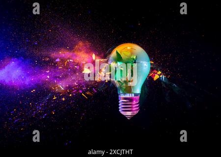 Broken light bulb exploding with colorful powder on a black background Stock Photo