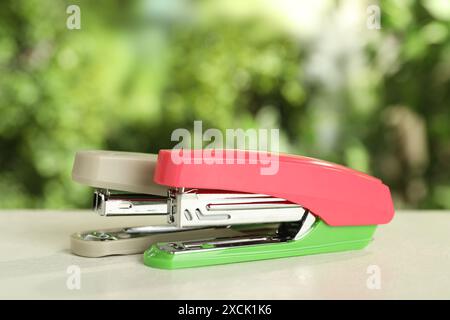 Two staplers on white table against blurred background Stock Photo