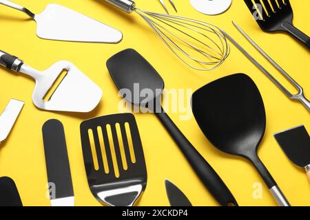Different spatulas and other kitchen utensils on yellow background, closeup Stock Photo