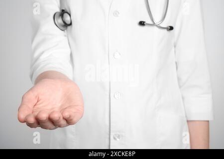 Doctor holding something on light grey background, closeup Stock Photo