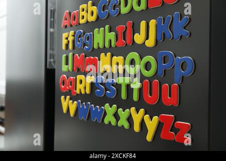 Alphabetical order. Many bright magnetic letters on fridge indoors Stock Photo