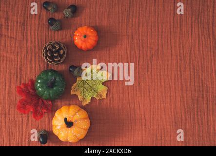 Creative trendy autumn or fall layout made with colorful fallen leaves, pumpkins, pinecone and nuts with copy space on brown muslin background. Stock Photo