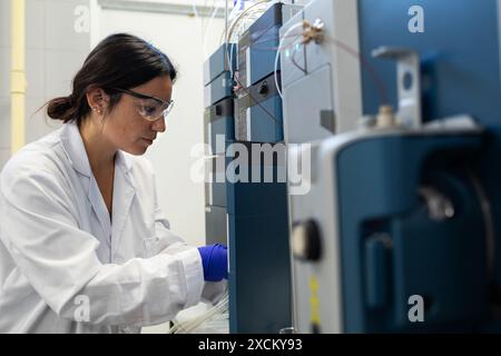 Side-view of a woman scientist analyzing samples in a laboratory using a mass spectrometer. Stock Photo