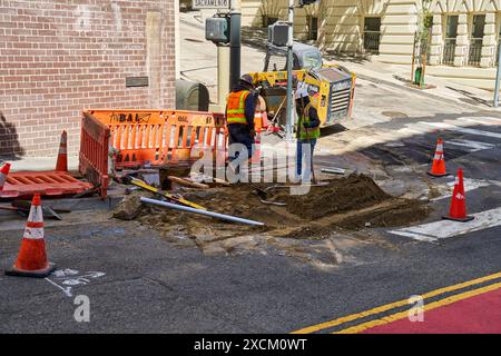 San Francisco, California, United States of America - June 14, 2024: Two construction workers in safety vests and helmets on a construction site in the city of San Francisco. They are working on a trench, surrounded by safety cones and machines *** Zwei Bauarbeiter in Warnwesten und Helmen auf einer Baustelle in der Stadt San Francisco. Sie arbeiten an einem Graben, umgeben von Sicherheitskegeln und Maschinen Stock Photo