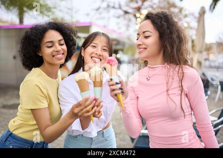 Three multiethnic young friends enjoying ice cream outdoors Stock Photo